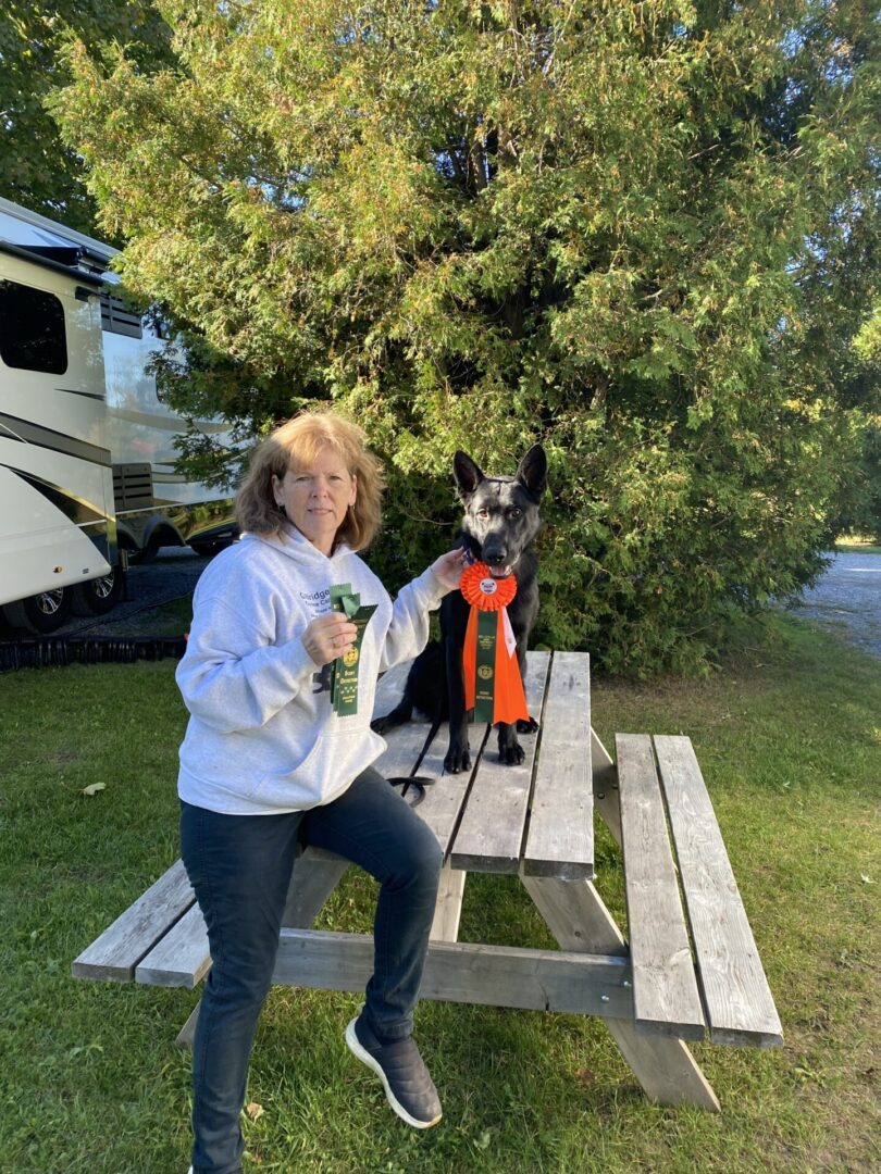 Woman sitting on a picnic table holding a dog with a fire extinguisher.