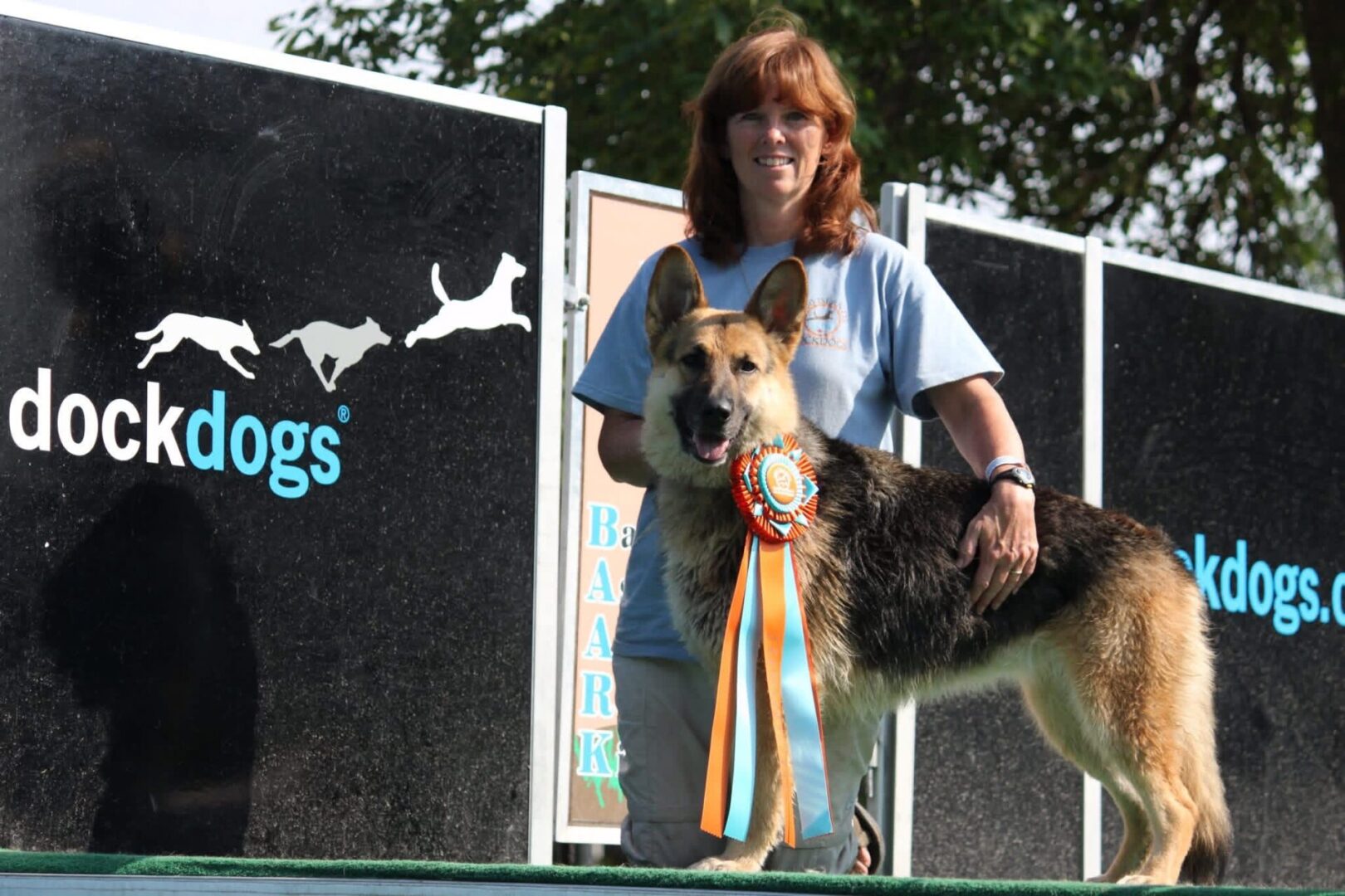 A woman with a dog holding a ribbon at a competition.